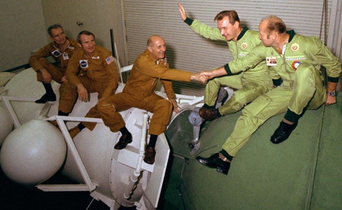 Астронавты и космонавты Дональд Слейтон, Вэнс Бранд, Томас Стаффорд, Валерий Кубасов и Алексей Леонов сидят на макетах космических кораблей «Аполлон» и «Союз» в Космическом центре Джонсона НАСА, Хьюстон, США, 1975 год